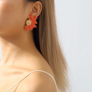Detail of red floral earrings with gold edges and metallic textures on female model