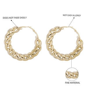 Close-up of chunky gold chain hoop earrings with high-polished metallic finish