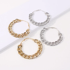 Macro shot of thick chain links on gold and silver hoop earrings on a geometric stand