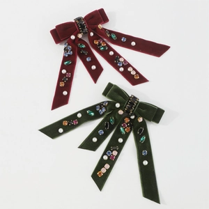 Detail of luxury velvet bow clips with colorful crystals and pearls in red and green
