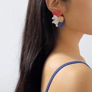 Detail of model wearing vintage floral stud earrings with red white and blue enamel petals