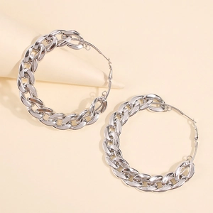 Macro view of chunky silver chain hoop earrings on a minimalist beige background