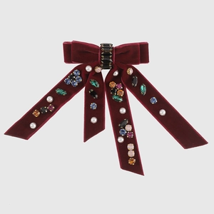 Macro shot of burgundy velvet bow hair clip with colorful rhinestones and white pearls