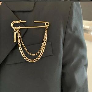 Gold-plated safety pin brooch with double layered chains on a black suit jacket