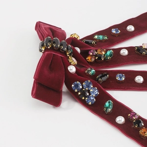 Close-up of velvet bow hair clip featuring colorful rhinestones and white pearls