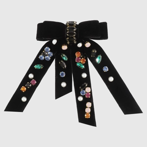 Macro detail of black velvet bow hair clip with colorful rhinestones and pearls