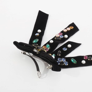 Detailed macro view of black velvet bow hair clip featuring colorful crystals and pearls