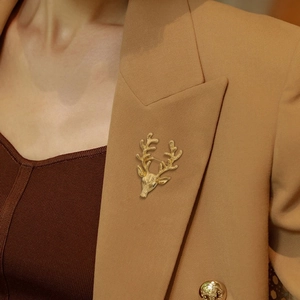Detail of a bright gold stag head brooch pinned on a brown suit blazer lapel