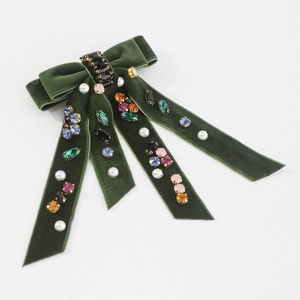 Detail of green velvet bow hair clip with colorful rhinestones and white faux pearls