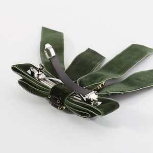 Detailed side view of dark green velvet bow hair clip with rhinestone center and metal clip