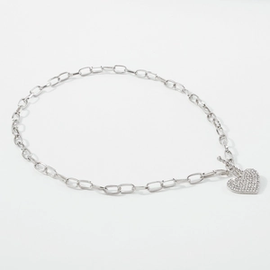 Macro shot of silver paperclip chain with heart pendant featuring pavé-set crystals and OT buckle