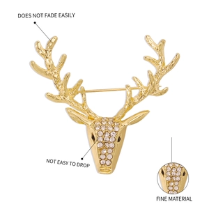 Détail d'une broche tête de cerf dorée ornée de strass blancs brillants et gravure fine