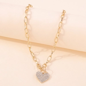 Macro detail of gold chunky chain necklace with sparkling heart pendant and rhinestones