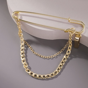 Detailed close-up of golden metal safety pin brooch with decorative dual hanging chains