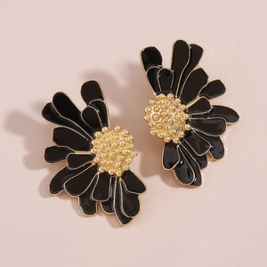 Macro view of vintage black enamel floral earrings with textured gold metal edges and centers