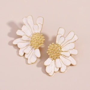 Macro detail of daisy flower earrings featuring white enamel petals and gold centers