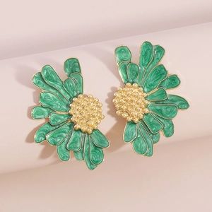 Macro shot of green enamel daisy earrings with golden metal petals and vintage texture