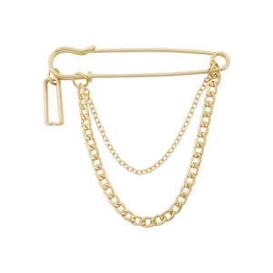 Macro shot of gold safety pin brooch featuring chunky curb chains and geometric pendant