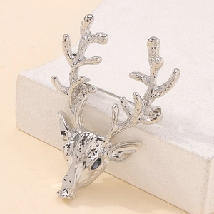 Détail macro d'une broche cerf argentée avec texture martelée et gemme foncée sur l'oeil