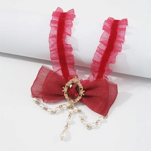 Macro detail of wine red velvet bow accessory with oval gemstone and pearl tassels