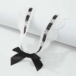 Detail of white lace choker with black satin ribbon and bow on a white stand