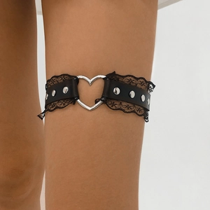 Détail de jarretière en dentelle noire avec anneau cœur et clous sur la jambe