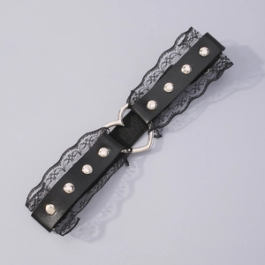 Détail de jarretière en dentelle noire avec boucles cœur argentées et clous punk