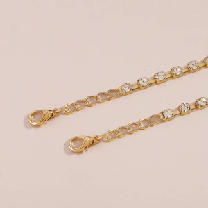 Macro-opname van vergulde klauwketting met sprankelende kristallen en karabijnsluiting