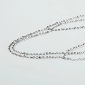 Macro-detail van meerlaagse zilveren lichaamsketting met strass-steentjes en verlengstuk