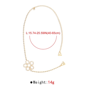 Detailed view of rhinestone gold shoulder chain with flower charm and metal hooks
