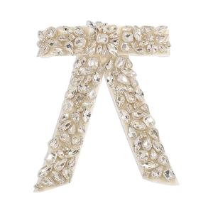Détail de la pince à cheveux nœud en strass étincelant sur base de satin blanc et cristaux
