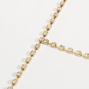 Detail van de goudkleurige ketting met fonkelende strassteentjes en klauwzetting