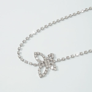 Macro shot of a sparkling silver butterfly body chain with white rhinestones on gray background