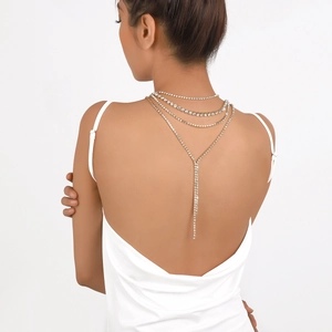 Close-up of layered rhinestone back chain necklace on an elegant white backless evening dress