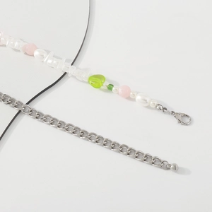 Detalle de cadena para el cuerpo con perlas irregulares y un corazón verde central