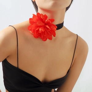 Détail du ras du cou avec grande fleur rouge en velours pour un look de soirée élégant