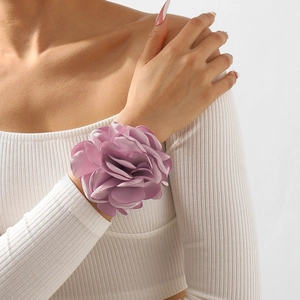 Détail d'un bracelet rose en satin violet avec des pétales en soie superposés et élégants