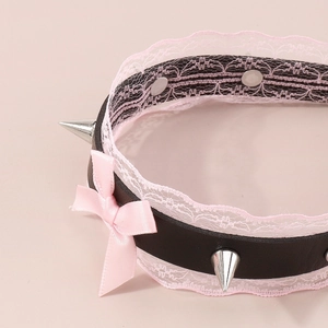 Detail of black leather punk choker with pink lace trim, silver spikes, and satin bow