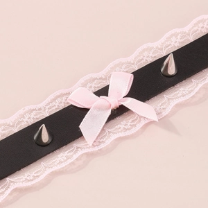 Detailed macro of a punk lace choker featuring pink silk bow and metallic silver spikes