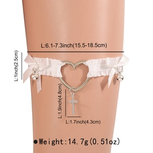 Détail d'une jarretière en dentelle blanche avec anneau cœur, croix et clochettes