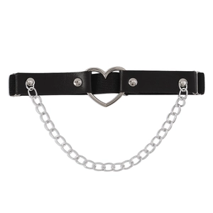 Dettaglio di una giarrettiera punk in pelle nera con cuore d'argento e catena metallica