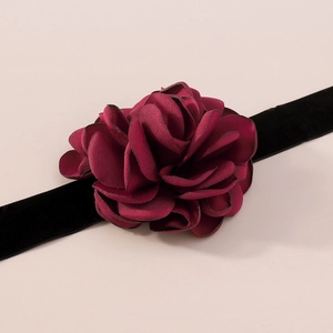Détail macro de pétales de fleurs bordeaux sur un ruban ras du cou en velours noir