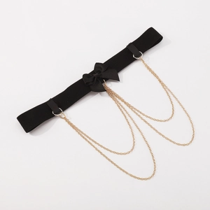 Detail of gothic black elastic leg garter with satin bow and gold chain tassels