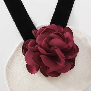 Détail d'un choker en velours élégant avec une rose en satin rouge sur une assiette