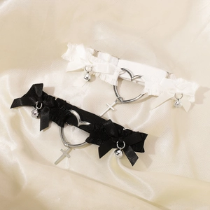 Détail de jarretières en dentelle avec nœuds en soie et pendentifs en croix