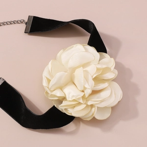 Détail d'une rose en tissu crème sur un large tour de cou en velours noir avec fermoir en métal
