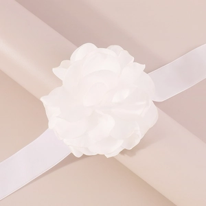 Détail d'une fleur élégante en tissu camélia blanc avec longs rubans de soie pure