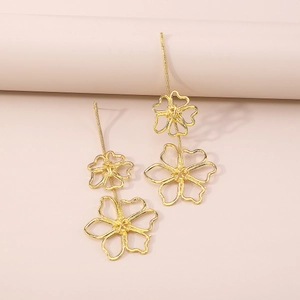 Detail of elegant gold hollow flower drop earrings on a minimalist aesthetic background