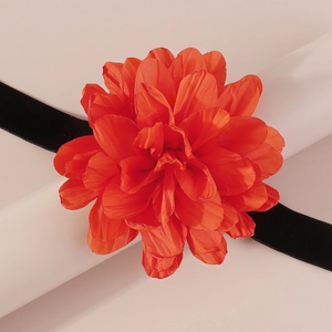 Gros plan d'un choker fleur en soie orange avec ruban en velours noir sur support blanc