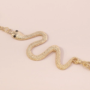 Macro detail of golden snake charm with black gem eyes and realistic scale texture